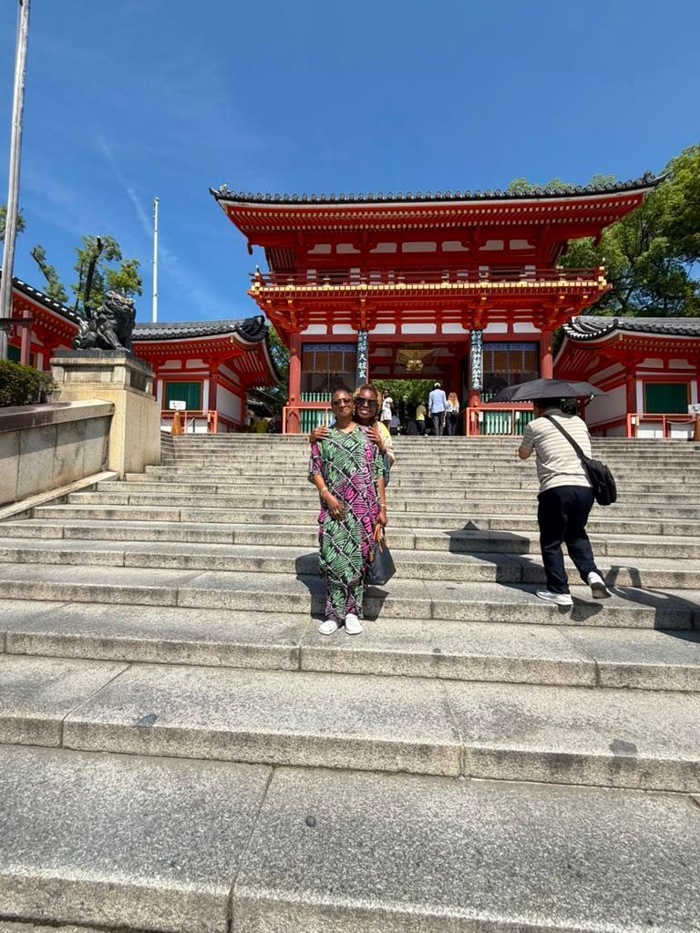 Friends posing on shrine steps beside a stone lion statue in Japan