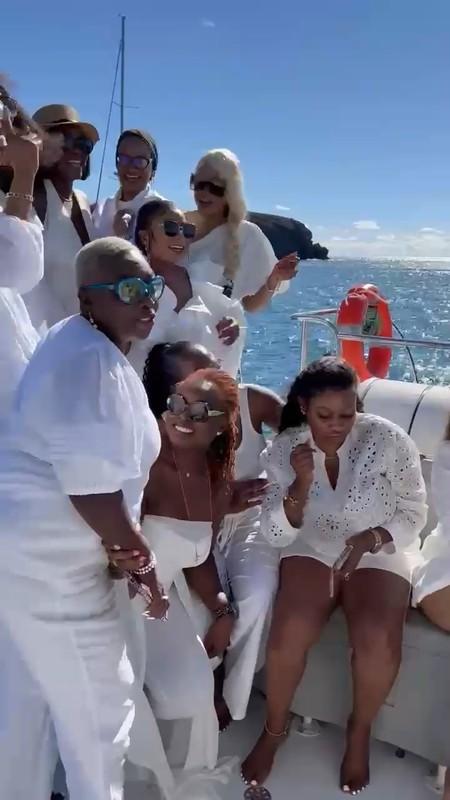 Group of friends in white outfits celebrating aboard a boat at sea
