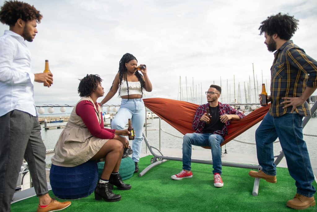 A diverse group of friends enjoying drinks and conversation on a yacht docked in Portugal.